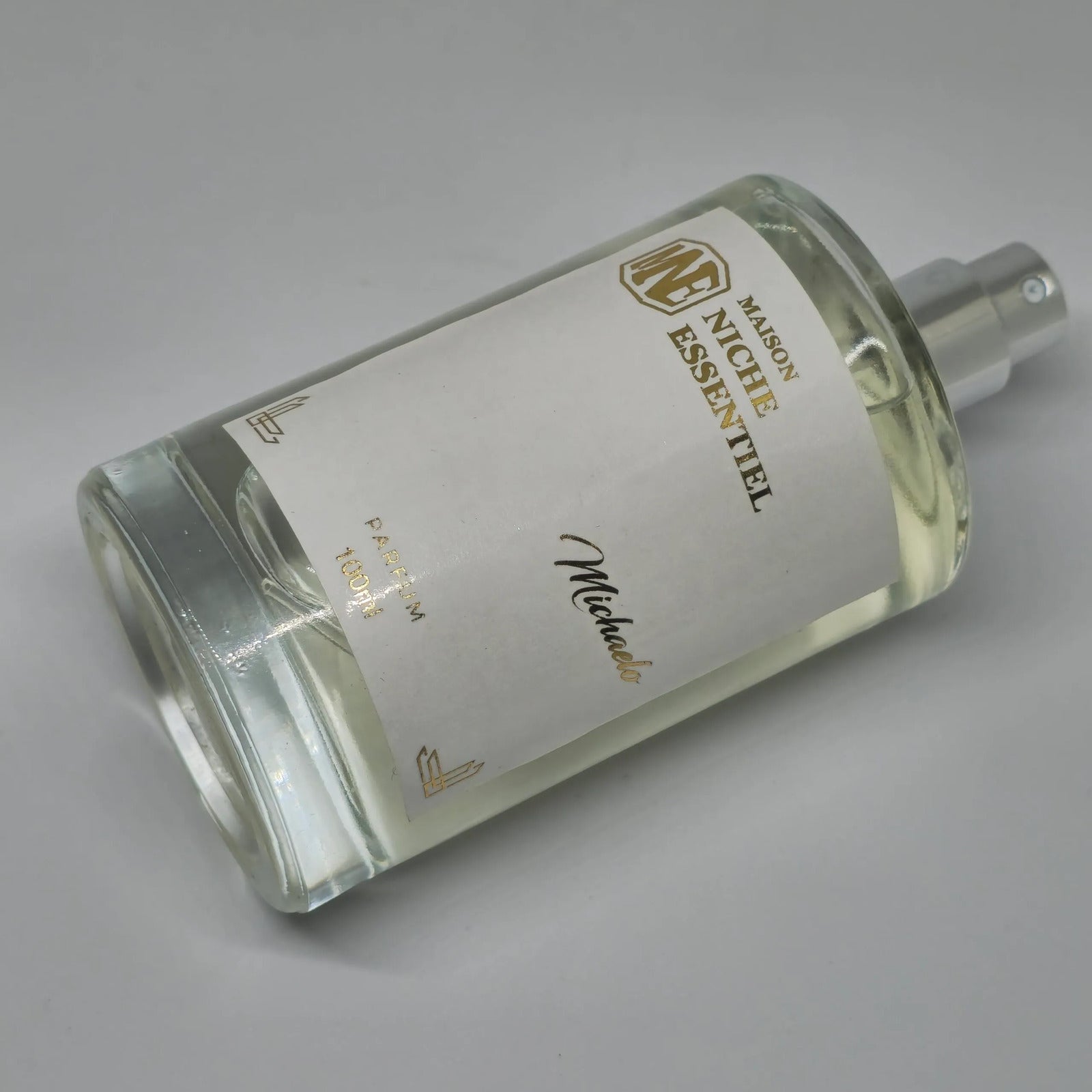 Transparent perfume bottle labeled Maison Nicky Essentiel with a silver spray nozzle.