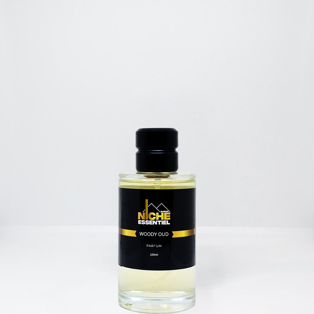 Bottle of Woody Oud perfume with a black cap and label featuring the brand name Niche Essentiel.