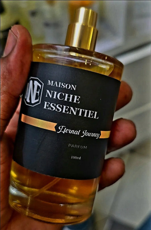 Hand holding a bottle of Maison Niche Essentiel Eternal Journey perfume with a black label.