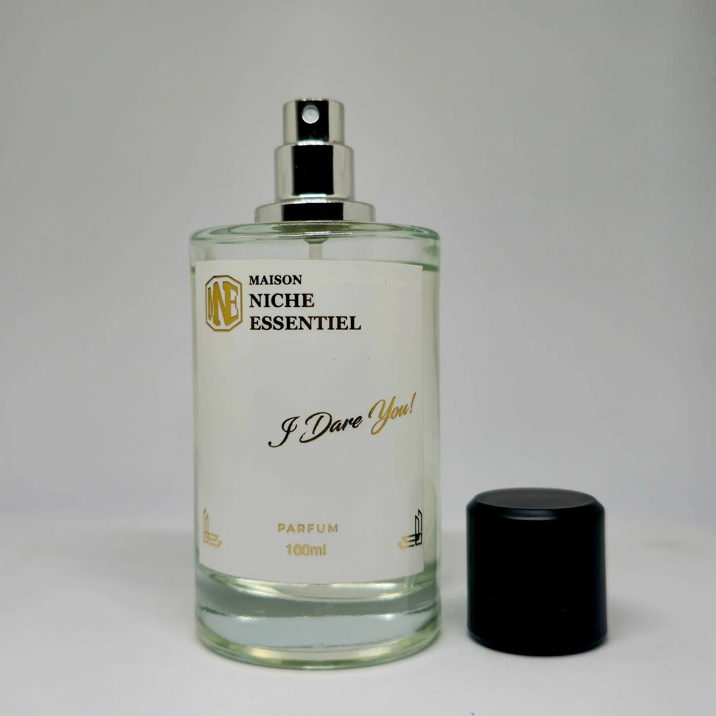 Clear glass perfume bottle labeled 'I Dare You!' with a black cap and silver spray nozzle.
