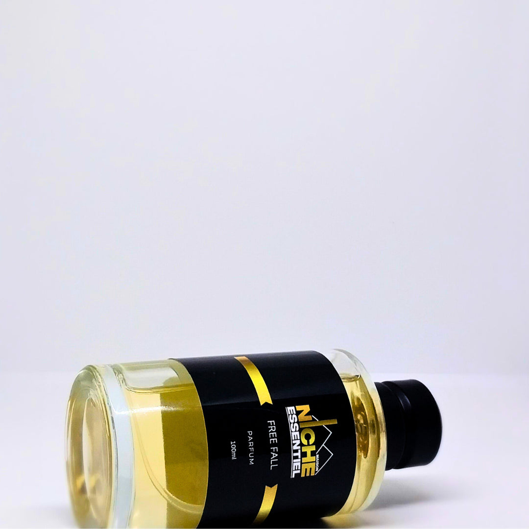 Transparent perfume bottle labeled 'Niche Essentiel Free Fall' with a black cap and gold accents.